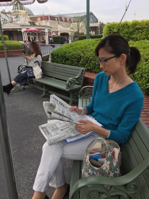 小倉アナもその一人。慣れないディズニーランドに不安げ。新聞を読み出す次第
